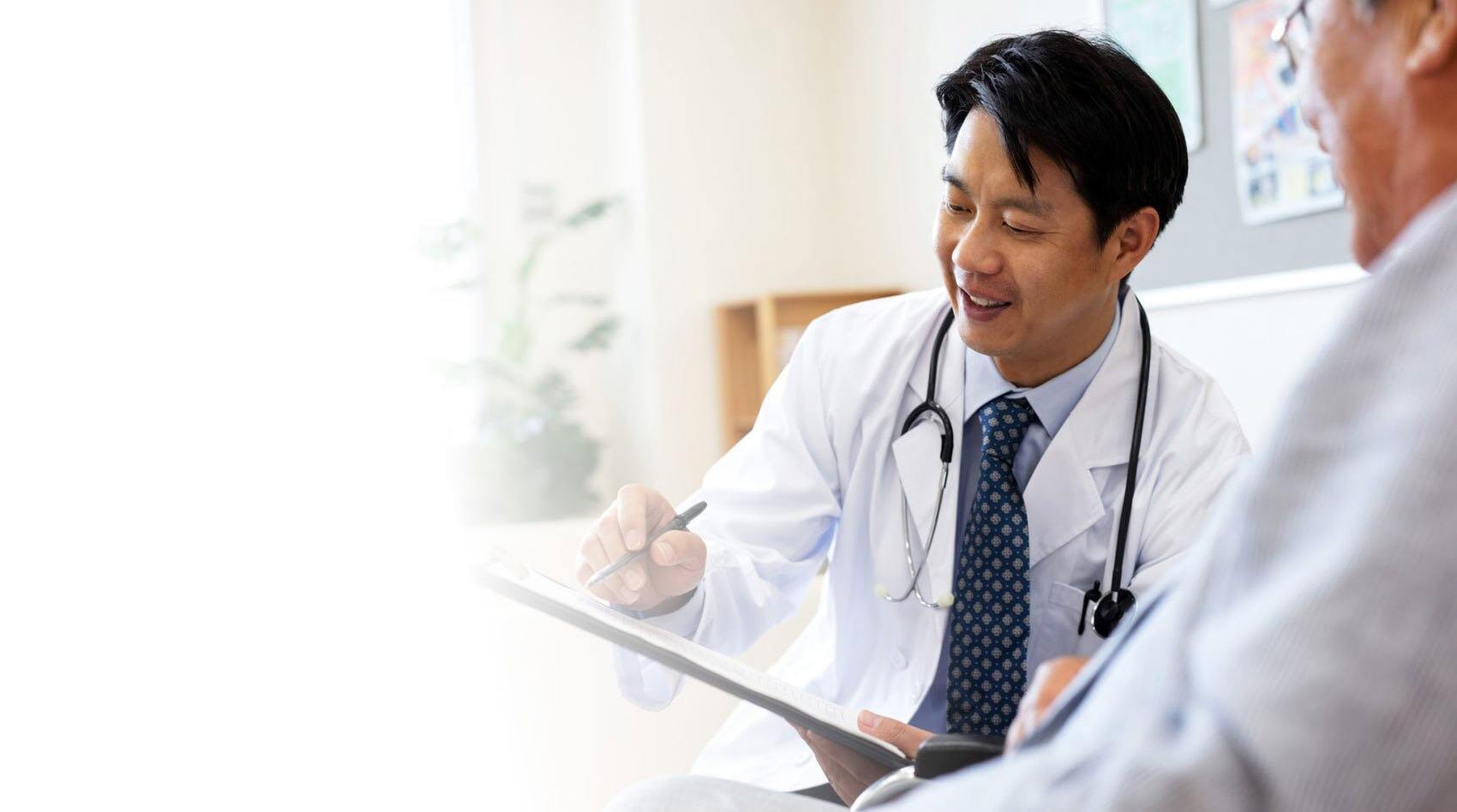 Arzt schreibt in die Krankenakte eines Patienten
